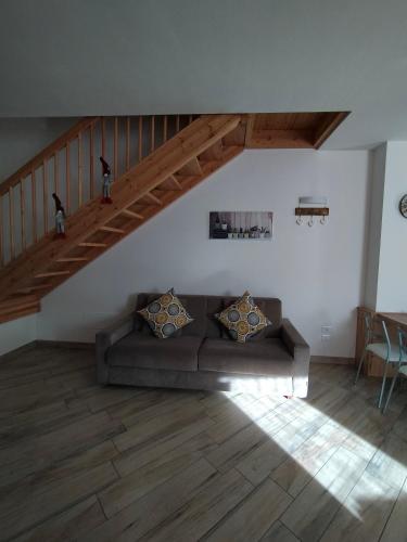 a living room with a couch and a staircase at Appartamento Morettina con terrazzo in Levico Terme