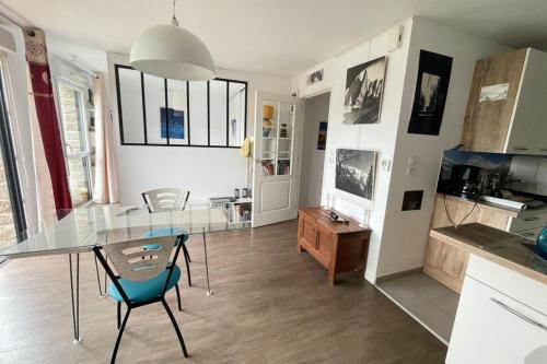 eine Küche mit einem Glastisch und Stühlen im Zimmer in der Unterkunft Studio récent Cosy - Ploemeur in Ploemeur