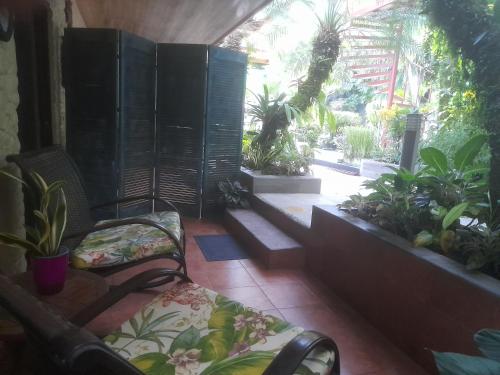 a porch with a couch and some plants at Coyaba Tropical Elegant Adult Guesthouse in Manuel Antonio