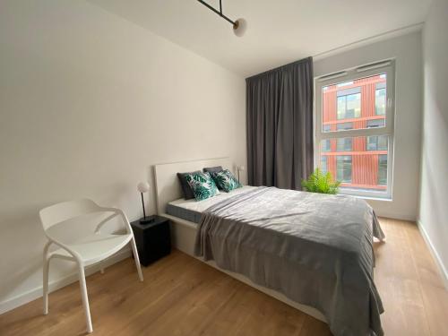 sypialnia z łóżkiem, krzesłem i oknem w obiekcie Apartamenty Fuzja - Komfortowe Mieszkania Blisko Centrum Łodzi w Łodzi