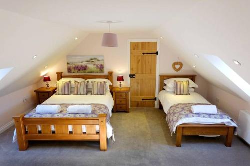 a attic bedroom with two beds and a staircase at Sycamore Tree Barn in Brecon