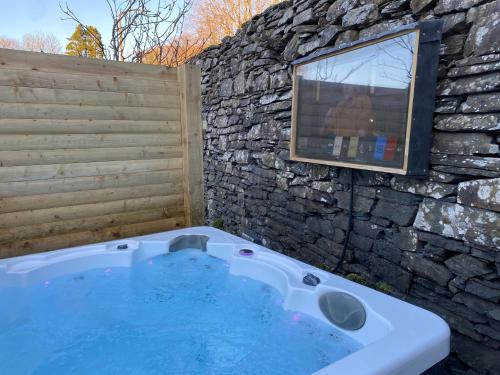 a bath tub with a stone wall and a window at Luxury 1 bed Villa - great location - Peaceful-Hot Tub in Bowness-on-Windermere