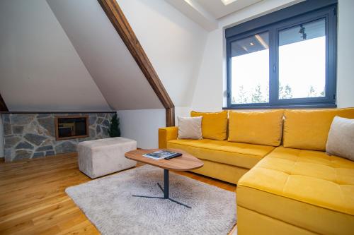 a living room with a yellow couch and a table at Titova Vila Zlatibor in Zlatibor