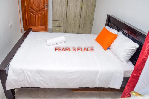 Meru的住宿－Pearl's Place，一间卧室配有一张带橙色枕头的大床