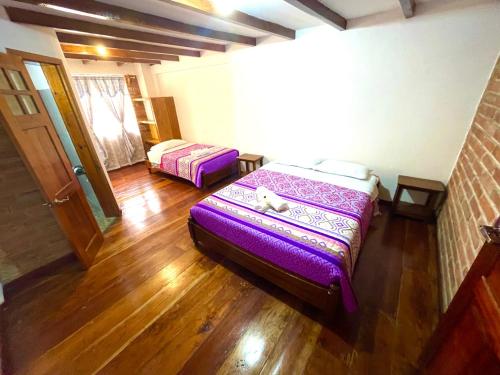 1 Schlafzimmer mit 2 Betten in einem Zimmer mit Holzböden in der Unterkunft Exedra de Galeria Cafe. Mindo- Ecuador in Mindo