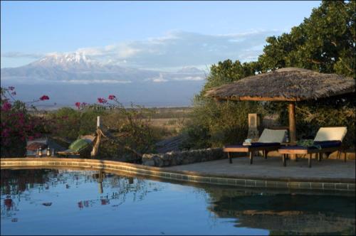 una piscina con tavolo, sedie e ombrellone di Kia Lodge ad Arusha