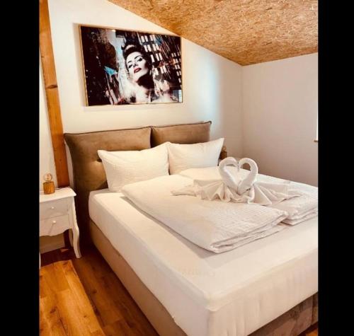 a bed with white sheets and a picture on the wall at Family Apartments Abuja in Rust