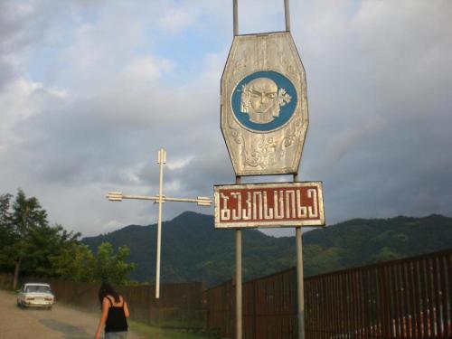 a woman walking past a sign for a bus stop at bukistsikhe in Chʼokhatauri