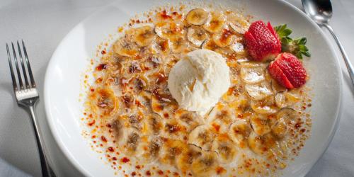 a white plate of cereal with bananas strawberries and ice cream at Pousada Les Roches in Itaipava