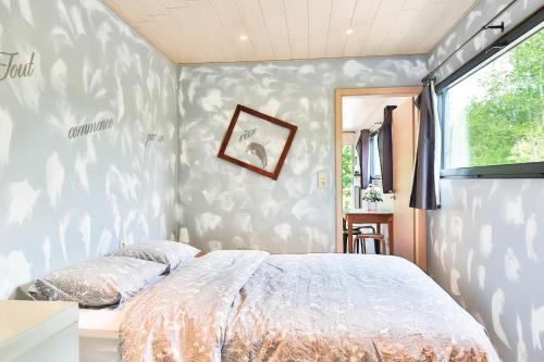 Tinyhouses - Domain "La vallée des Prés" في Bande: غرفة نوم بسرير وجدار مغطى بورق الجدران