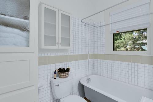 a white bathroom with a toilet and a bath tub at Twin Elm Cottage in Canyon Lake