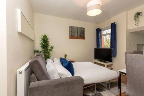 a bedroom with a bed and a couch and a television at Charming North London Apartment in London