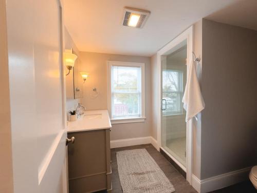 een badkamer met een douche, een wastafel en een spiegel bij Water Access 5-Bed 2-Bath Retreat in Barnstable