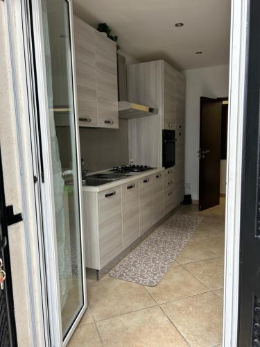 a kitchen with white cabinets and a glass doorway at Elly’s House in Bari