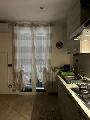 a kitchen with a window with curtains and a stove at Elly’s House in Bari