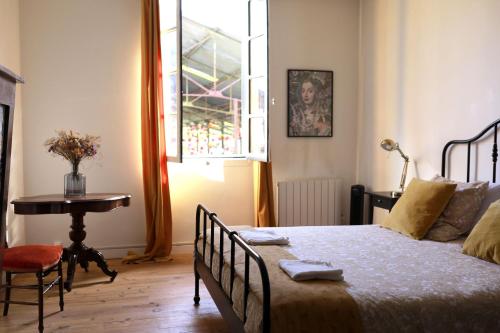a bedroom with a bed and a table and a window at Maison - Les Traversières in Eymet