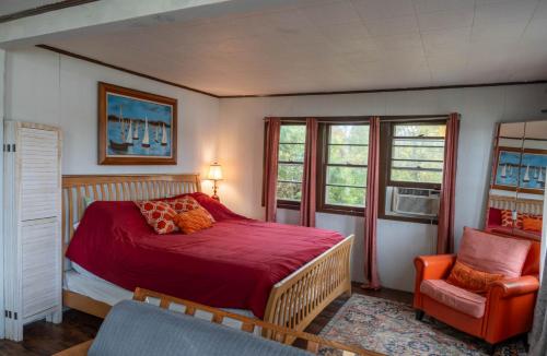 a bedroom with a bed and a chair and windows at Campau Lake Sunshine cottage in Cascade