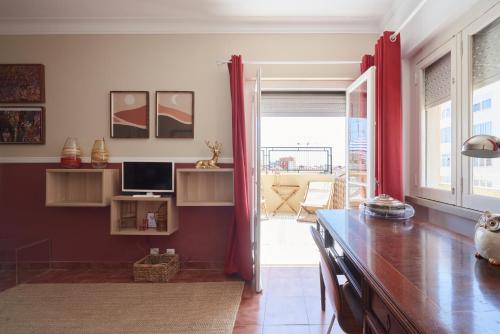 sala de estar con cortinas rojas y escritorio en Calm & Relaxing Apartment w/ Terrace in Almada en Almada