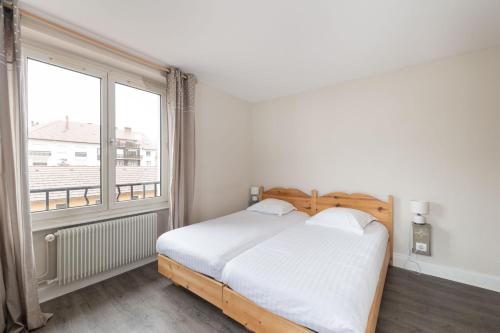 a bedroom with a bed and a large window at Hôtel De La Paix in Gérardmer