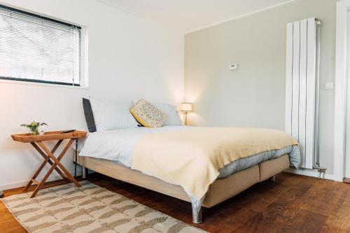 a white bedroom with a bed and a table at Ubi-iter? History, heritage and hospitality in Doesburg
