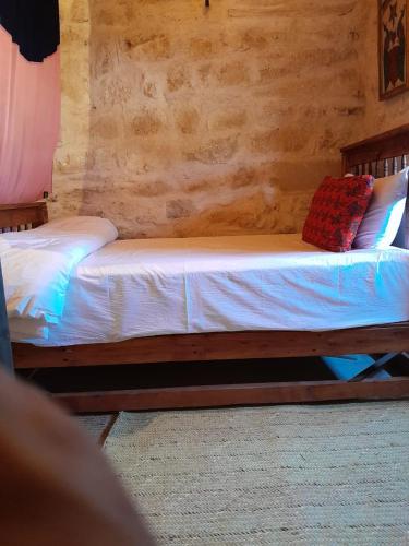 a bedroom with a bed with white sheets and red pillows at نزل كوفان التراثي Koofan Heritage Lodge in Salalah