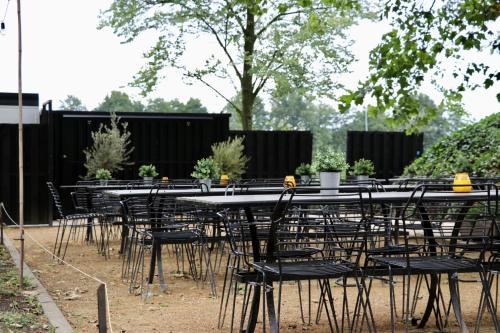 un grupo de mesas y sillas con plantas. en Camping de Zwammenberg, en De Moer