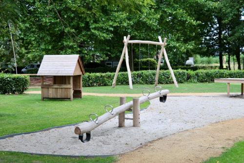 a playground with a wooden swing set and a bench at Camping de Zwammenberg in De Moer