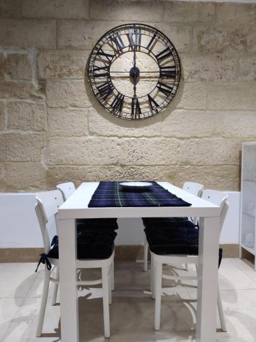 une table et des chaises blanches avec une horloge sur un mur dans l'établissement South Street 46, à La Valette