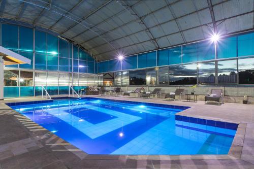 a large swimming pool in a building at night at Hotel Leão da Montanha in Campos do Jordão