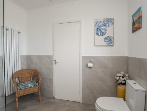 a bathroom with a toilet and a chair at Ewyn Gwyn in Pwllheli