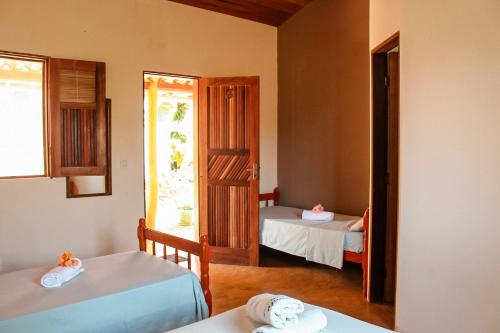 a room with two beds and a door with a window at Family Guest House in Ilha de Boipeba