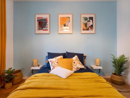 um quarto com uma cama amarela com quatro fotografias na parede em Le Haut Cloquais - SereniStay em Metz
