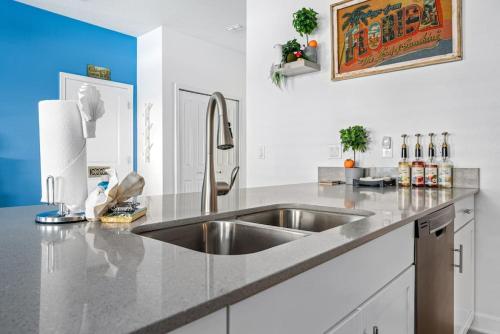 una cocina con fregadero de acero inoxidable y armarios blancos en New - Champions Gate 5-Bedroom, en Davenport