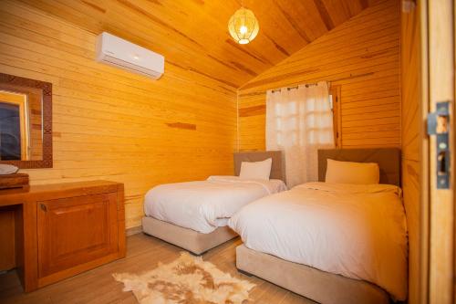 a bedroom with two beds in a wooden cabin at Dar Zayane in Khenifra