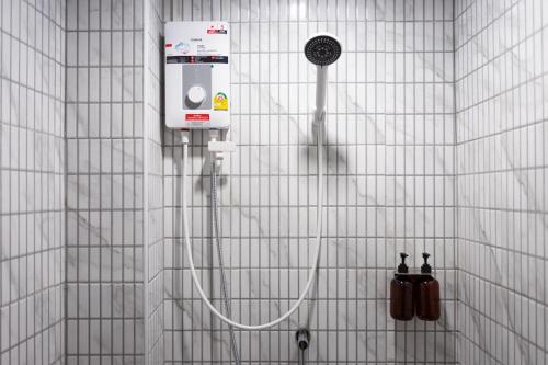 a shower in a white tiled bathroom with two bottles ofalcoholidated at A4 Cosy Twin large beds - Silom in Bangkok