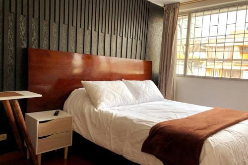 een slaapkamer met een bed met een houten hoofdeinde bij Apto confortable zona estratégica al Aeropuerto in Bogota