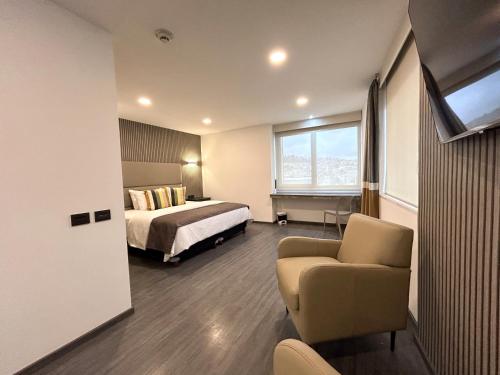 een hotelkamer met een bed en een stoel bij HUNICO HOTEL in Tulancingo