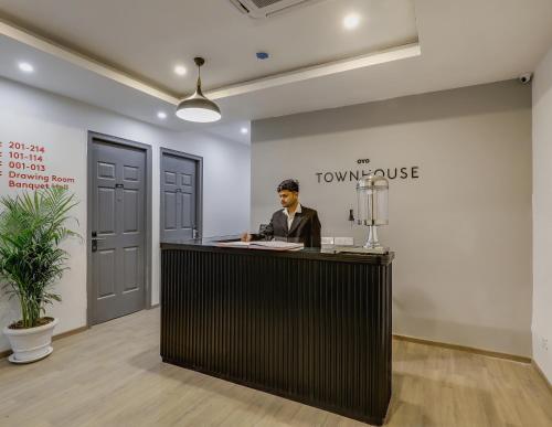 a man sitting at a reception desk in a room at Townhouse Siddharth Vihar Ghaziabad in Ghaziabad