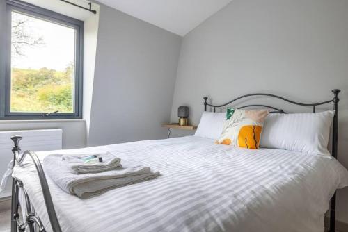 a bedroom with a bed with white sheets and a window at H3-Woodland Retreat-4BR-3B-Free Parking 