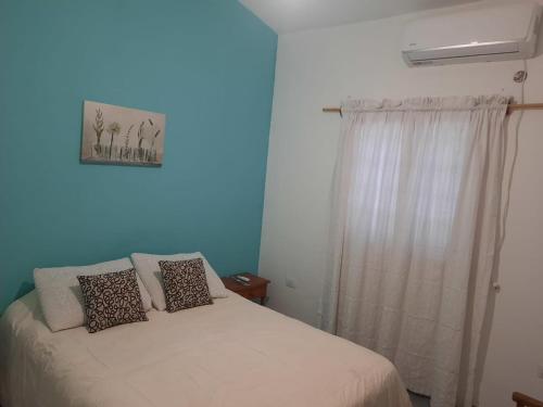 1 dormitorio con cama y ventana con cortina en casa familiar confortable en Santiago del Estero