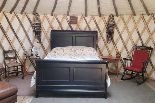 a bedroom with a black bed in a yurt at Rufus III Yurt on the river in Brownfield
