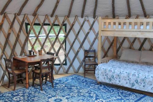 Allie Mae Yurt nestled in the woods في Brownfield: غرفة نوم بسرير وطاولة وكراسي