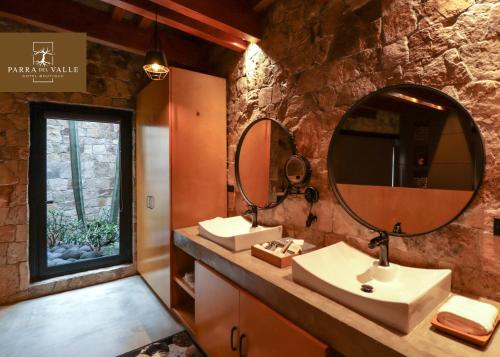 a bathroom with two sinks and a large mirror at Parra del Valle Hotel Boutique in Valle de Guadalupe