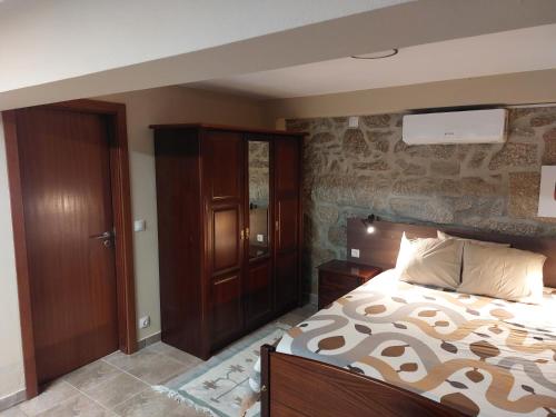 een slaapkamer met een groot bed en een houten kast bij Casa das Cortes - Serra da Estrela in Gouveia