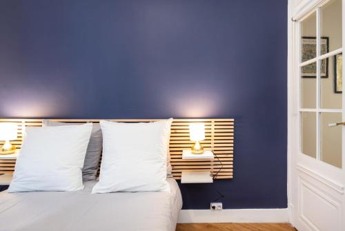 a blue bedroom with a bed with white pillows at Le Savoir in Lyon