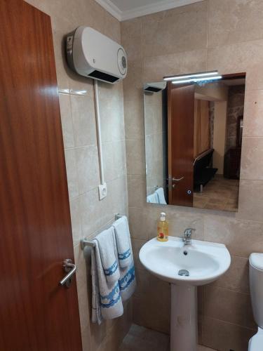 een badkamer met een wastafel, een toilet en een spiegel bij Casa das Cortes - Serra da Estrela in Gouveia