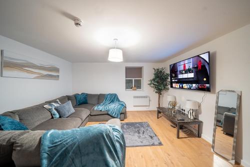 a living room with a couch and a flat screen tv at Cozy 2-Bedroom Ground-Floor Apt near Kirkstall Shopping Centre in Leeds
