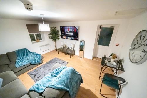 a living room with a couch and a clock at Cozy 2-Bedroom Ground-Floor Apt near Kirkstall Shopping Centre in Leeds