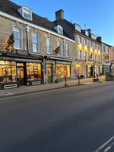 a street with a group of stores on a city street at Crown & Cushion Hotel in Chipping Norton