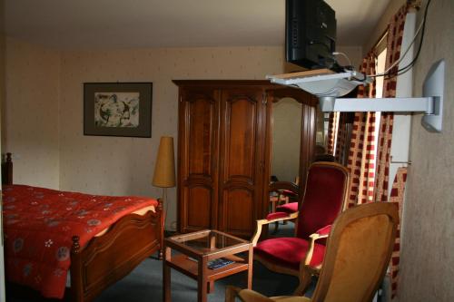 a bedroom with a bed and a chair and a cabinet at Le Logis du Pré Braheux in Saint-Nabord